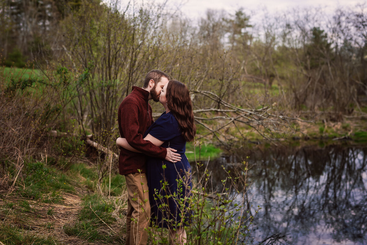 engaged couple kissing at pond during early sprint engagement session by nh engagement photographer Lisa Smith Photography