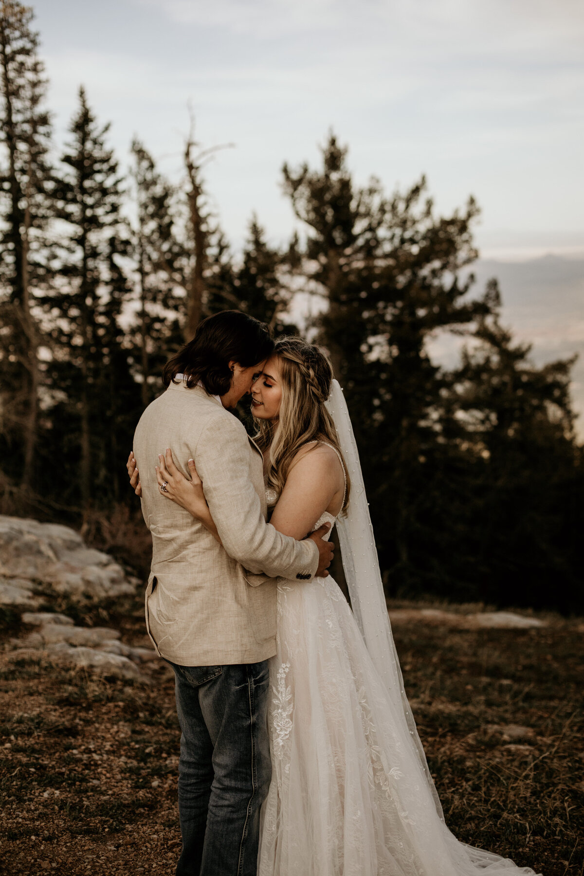 bride and groom about to kiss on top of a mountain