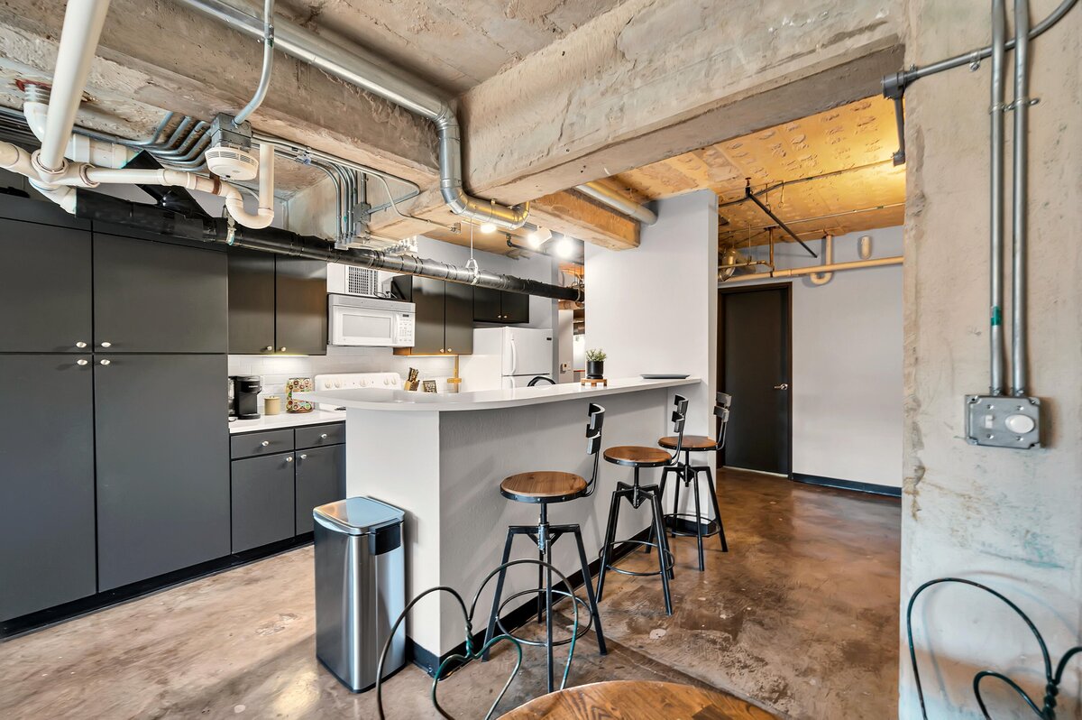 Kitchen area with island seating in this one-bedroom, one-bathroom industrial vacation rental condo with free Wifi, onsite laundry, and space for four in the historic Behrens building of downtown Waco, TX.