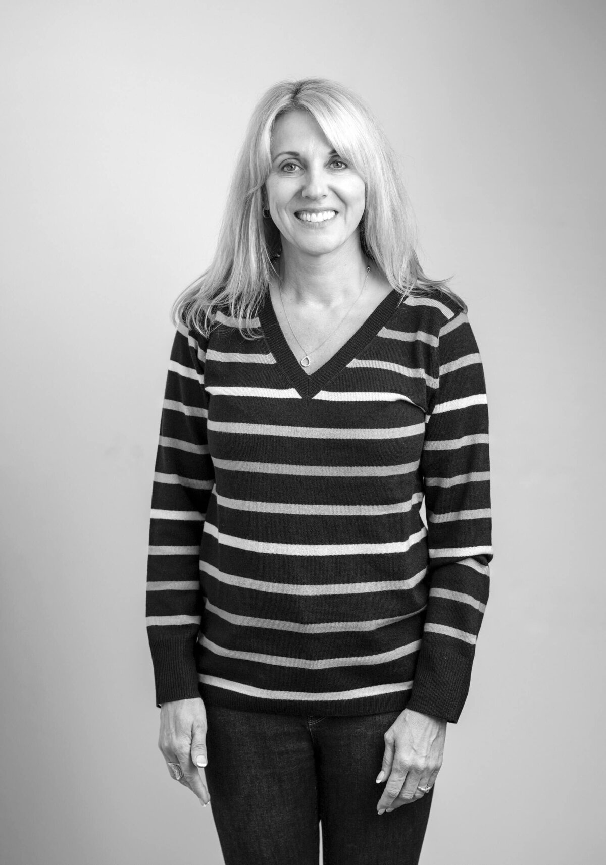 Before shot of a woman in a casual striped shirt with a relaxed smile, looking directly at the camera.