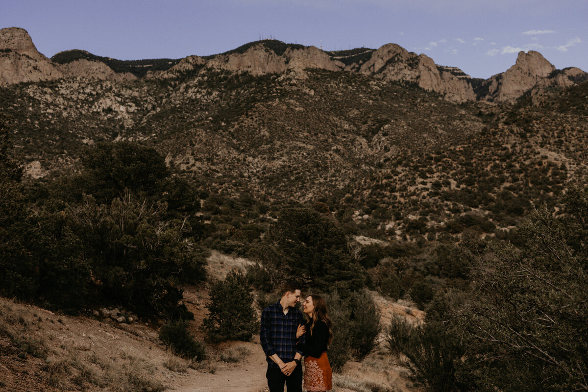 engaged couple standing in front of the Sandia mountains in Albuquerque