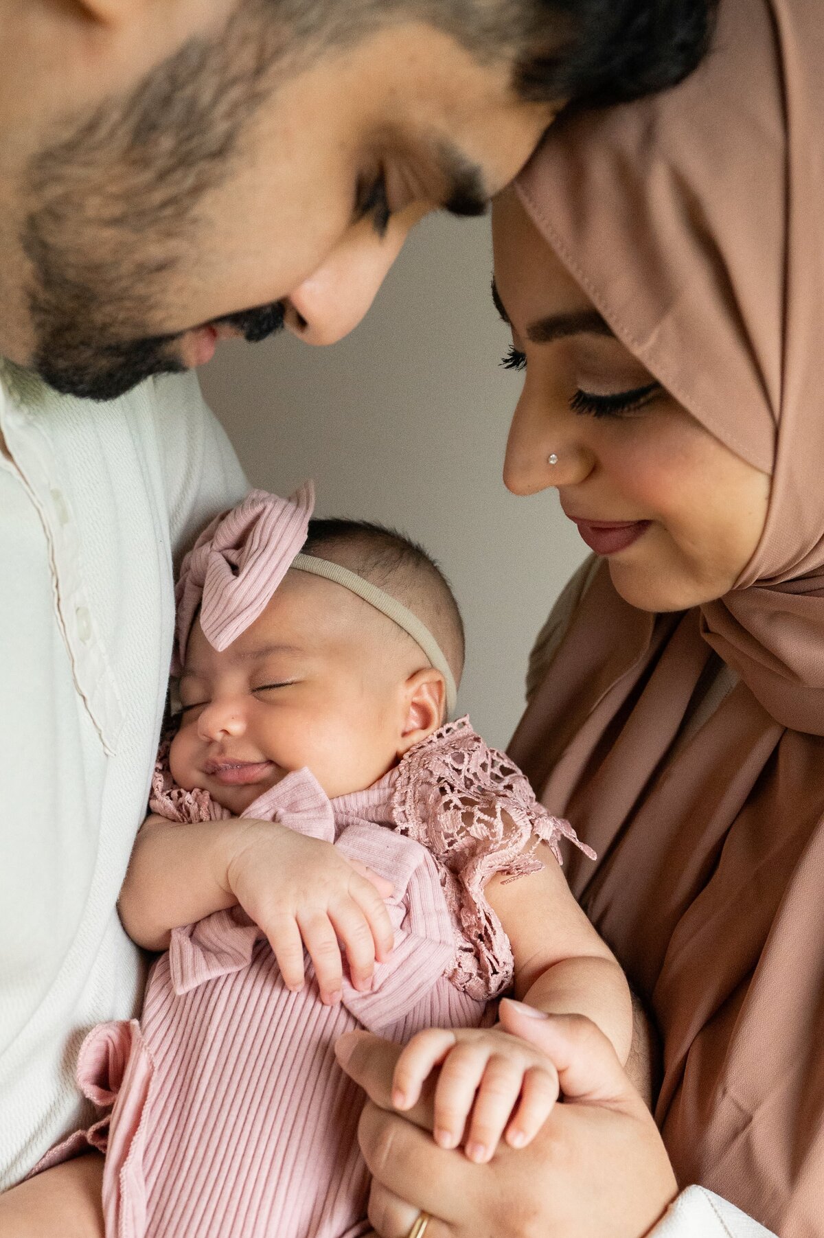mom and dad holding newborn baby girl while she is sleeping