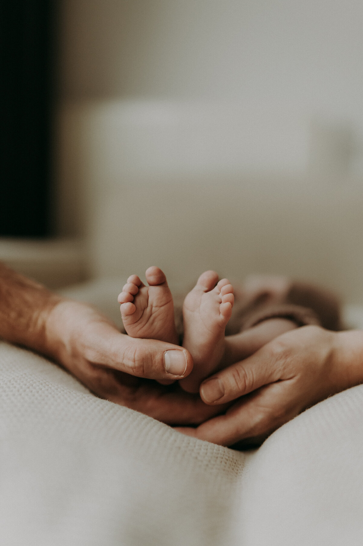 Detailfoto van voeten van een baby en handen van de ouders.