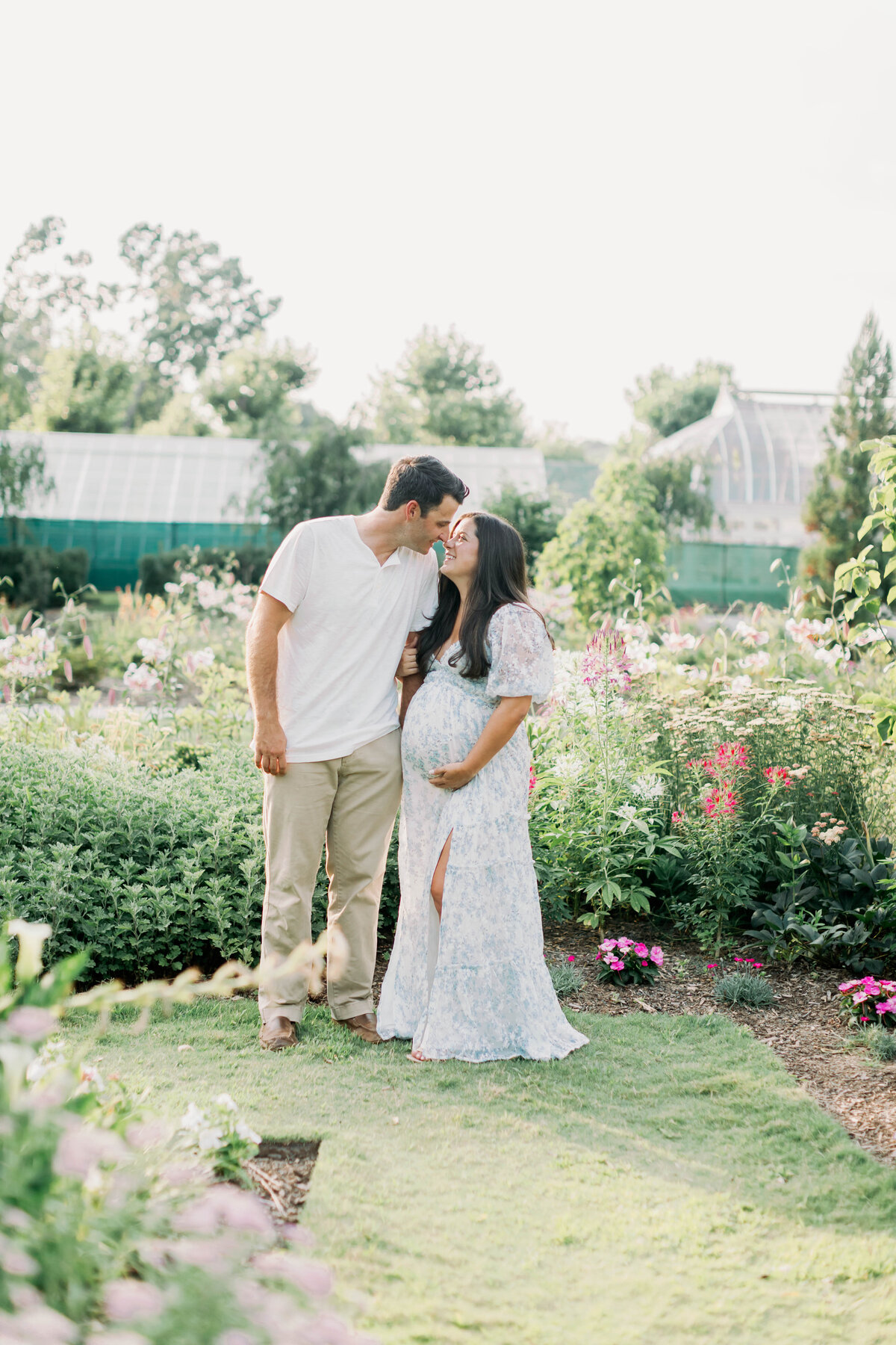 pregnant lady kissing husband in flower garden