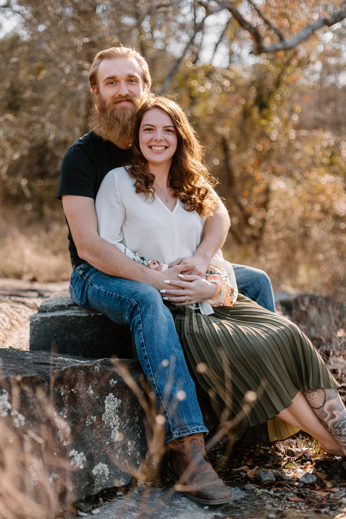 engaged couple sitting on a rock