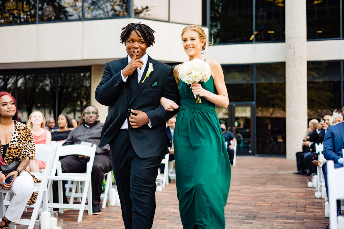 One of the top wedding photos of 2021. Taken by Adore Wedding Photography- Toledo, Ohio Wedding Photographers. This photo is of a groomsman walking a bridesmaid down the aisle at a wedding ceremony