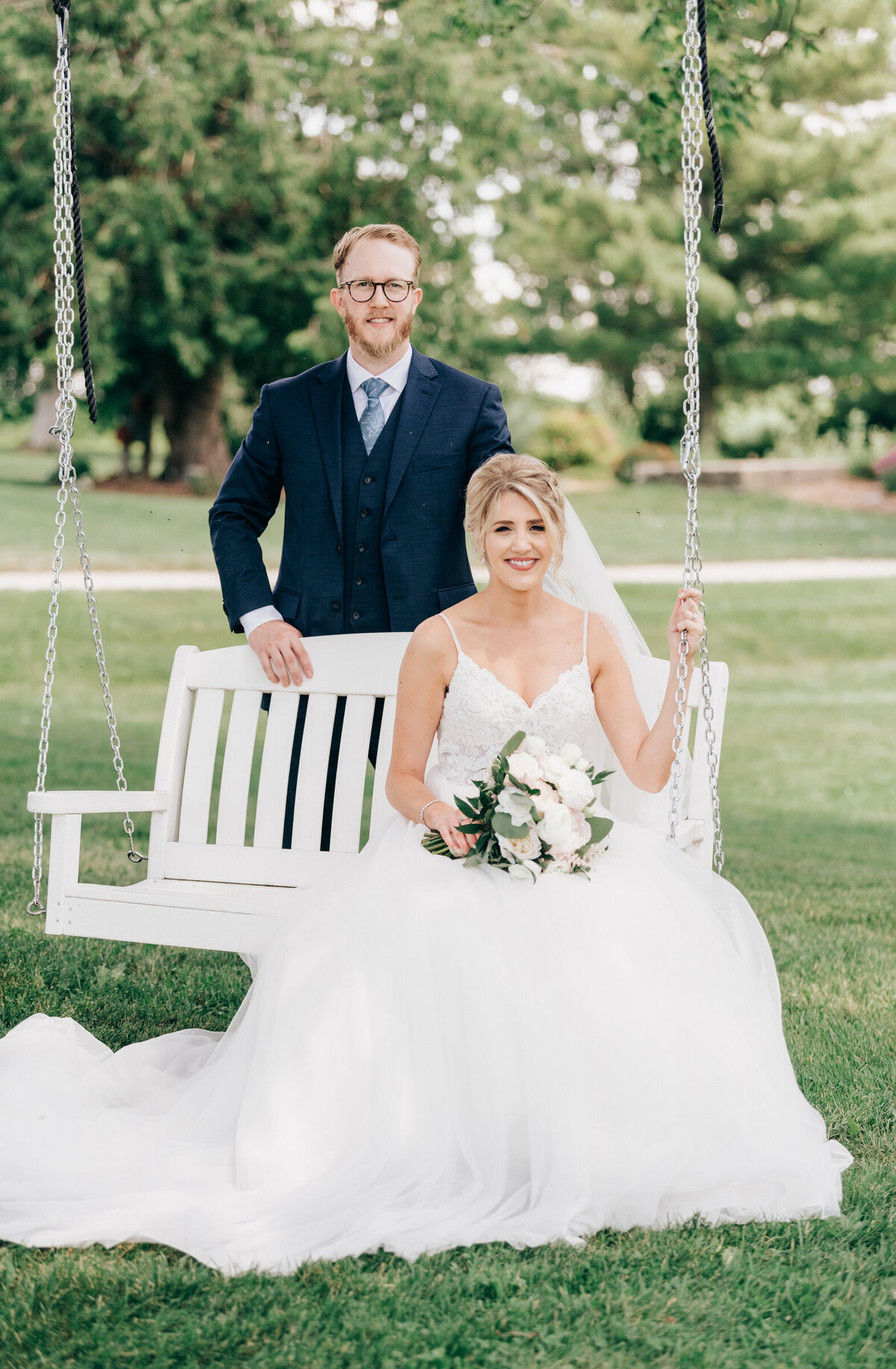 Elegant bride and groom sit on gorgeous outdoor tree swing at Willow Creek Barn photographed by Nova Markina