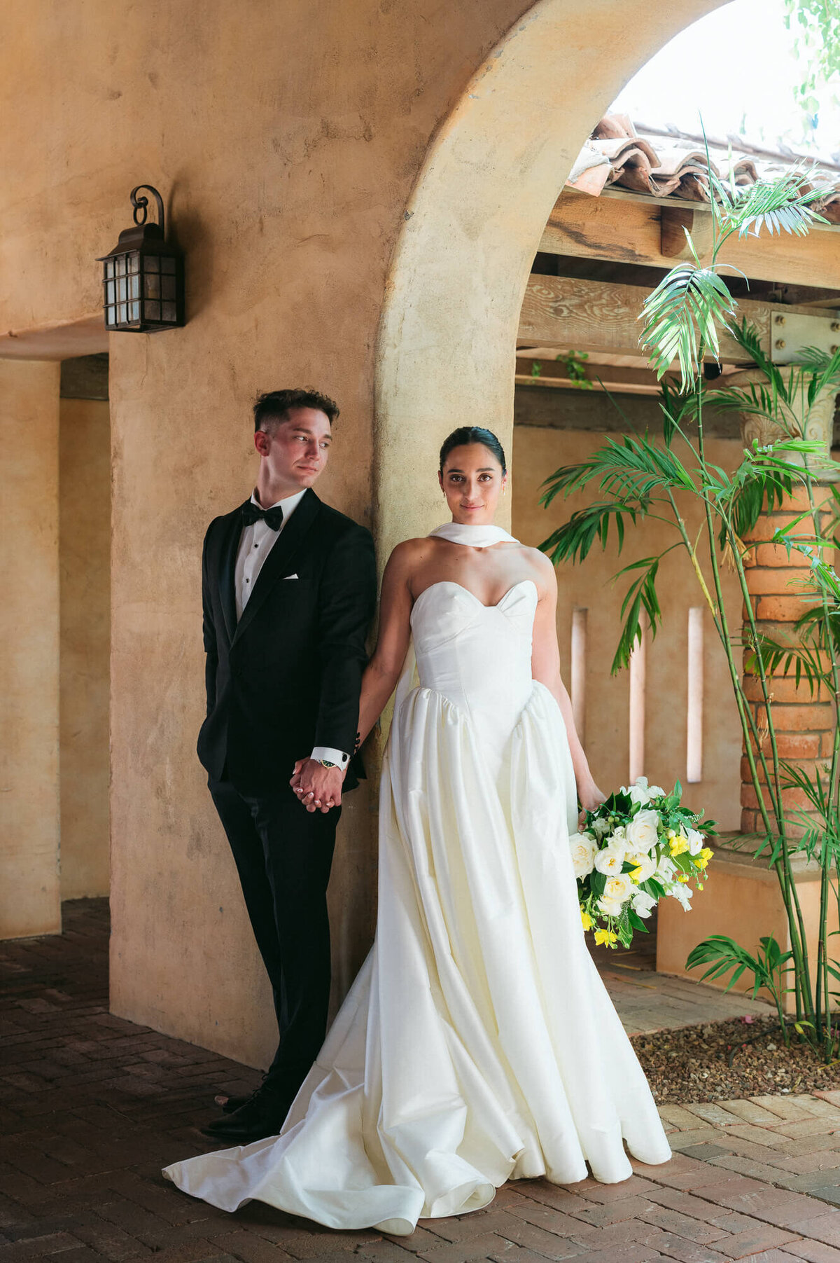 Bride and groom holding hands under the arches of Royal Palms in Scottsdale, captured by an Arizona wedding photographer.