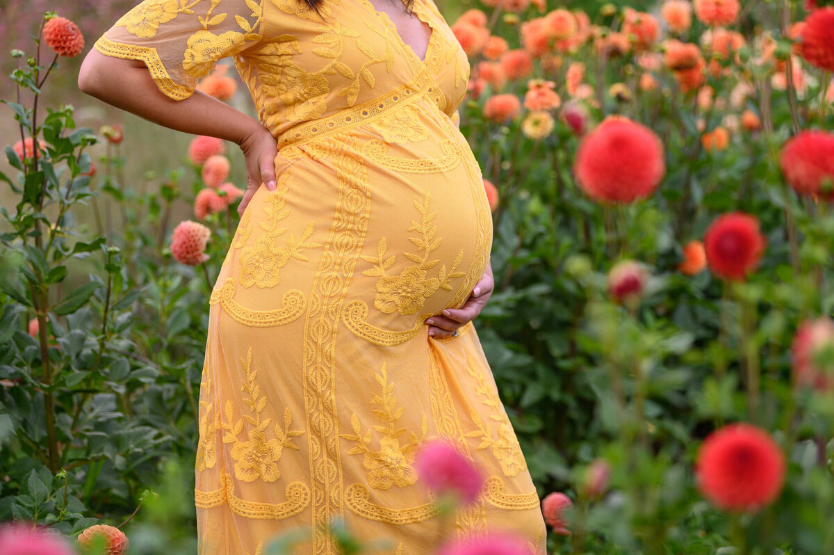 up close photo of a pregnant woman wearing a yellow dress in a flower field for her Burlington, Ontario Maternity photos