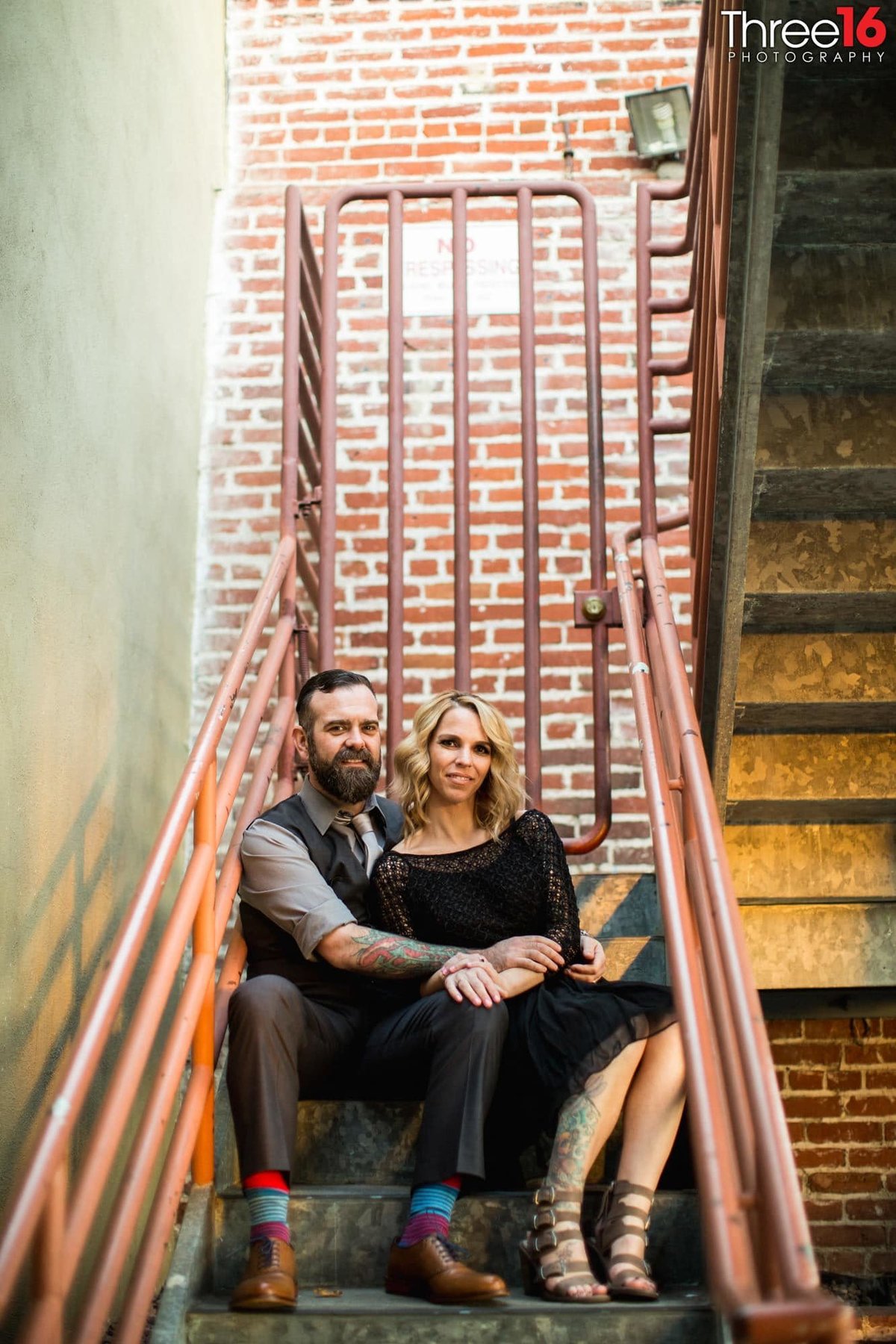 Engaged couple cozy up together sitting on an old outdoor staircase