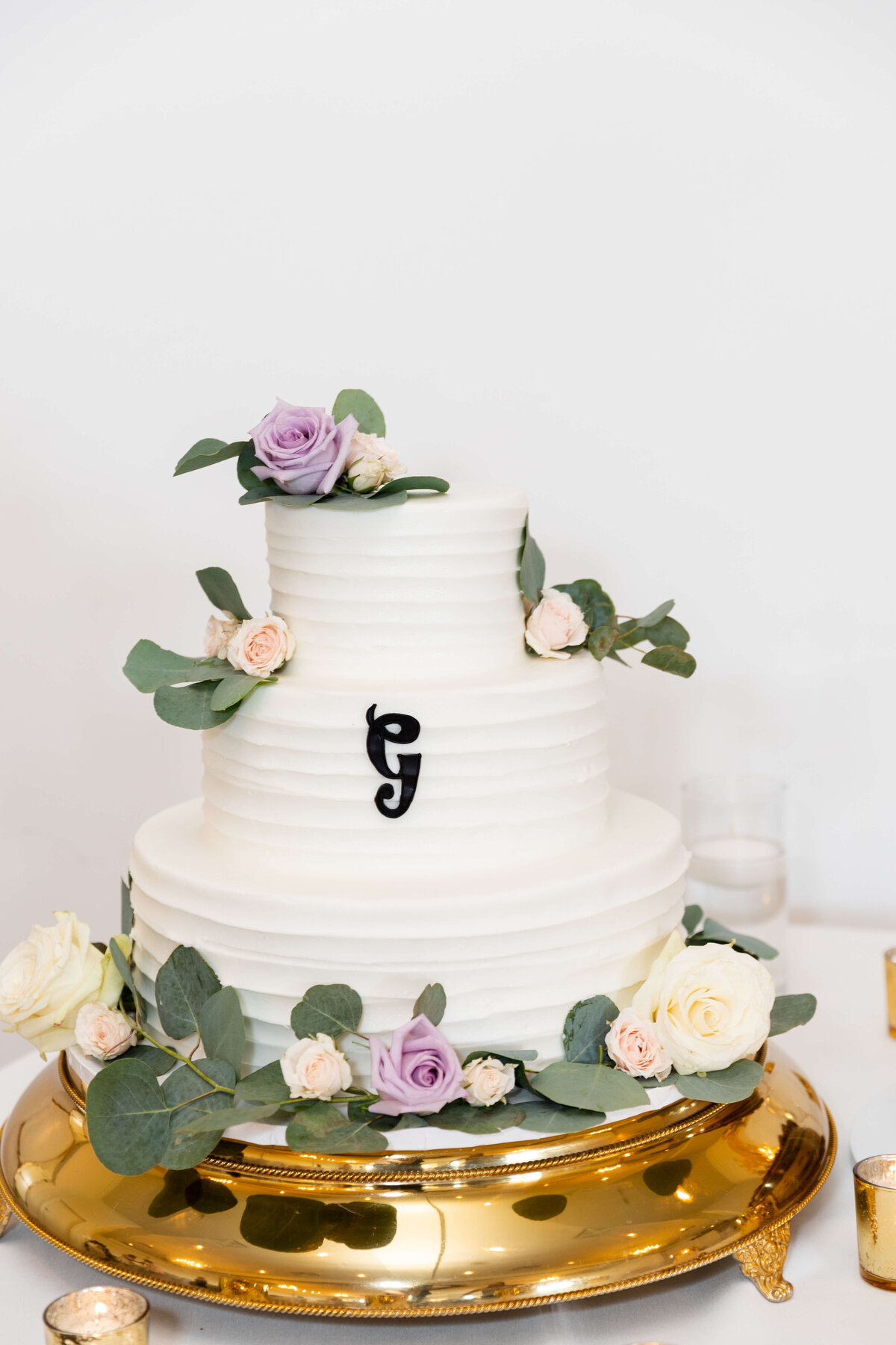 White 3 tiered wedding cake decorated with greenery and florals
