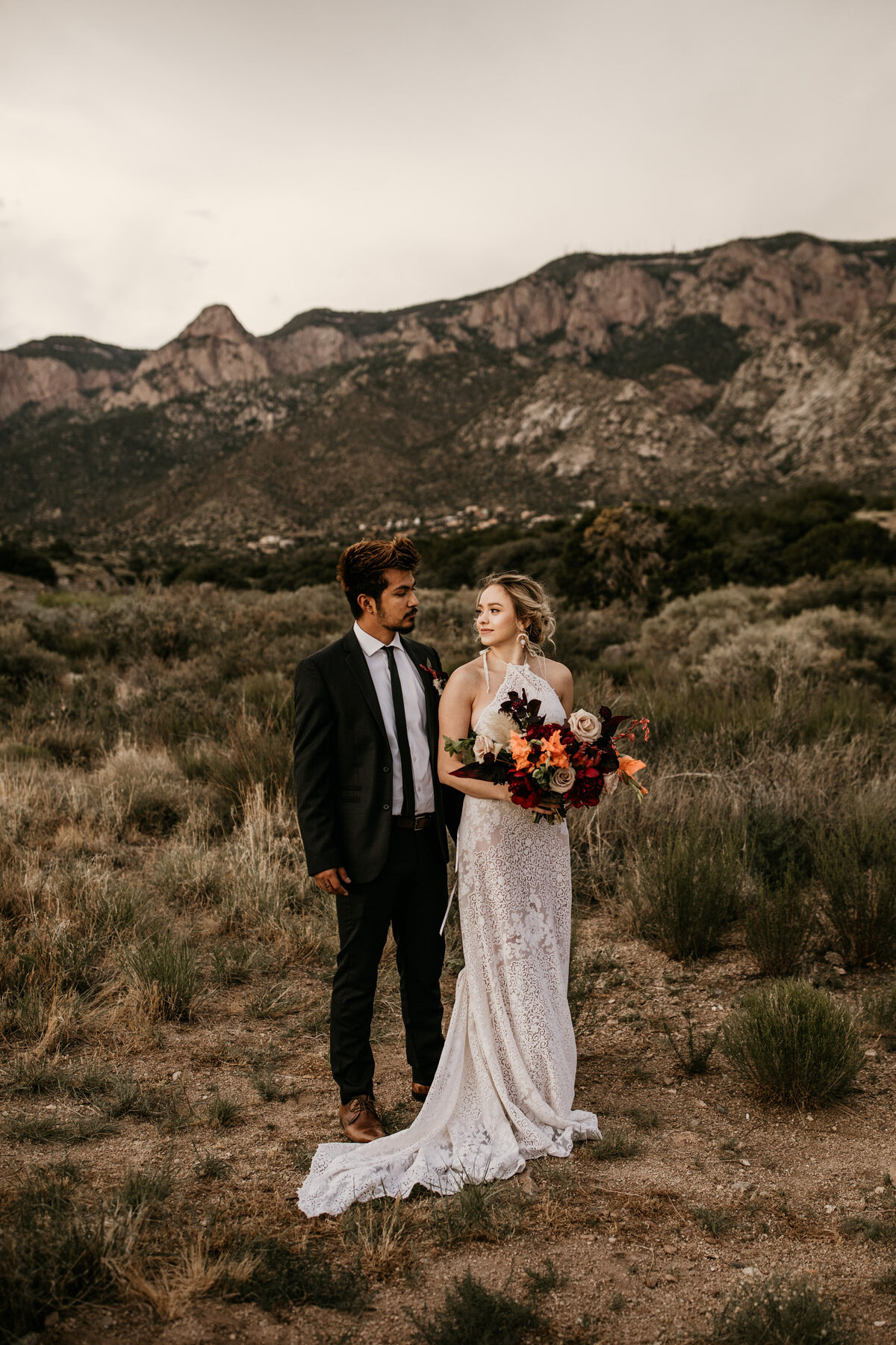 bride and groom standing in front of a mountain
