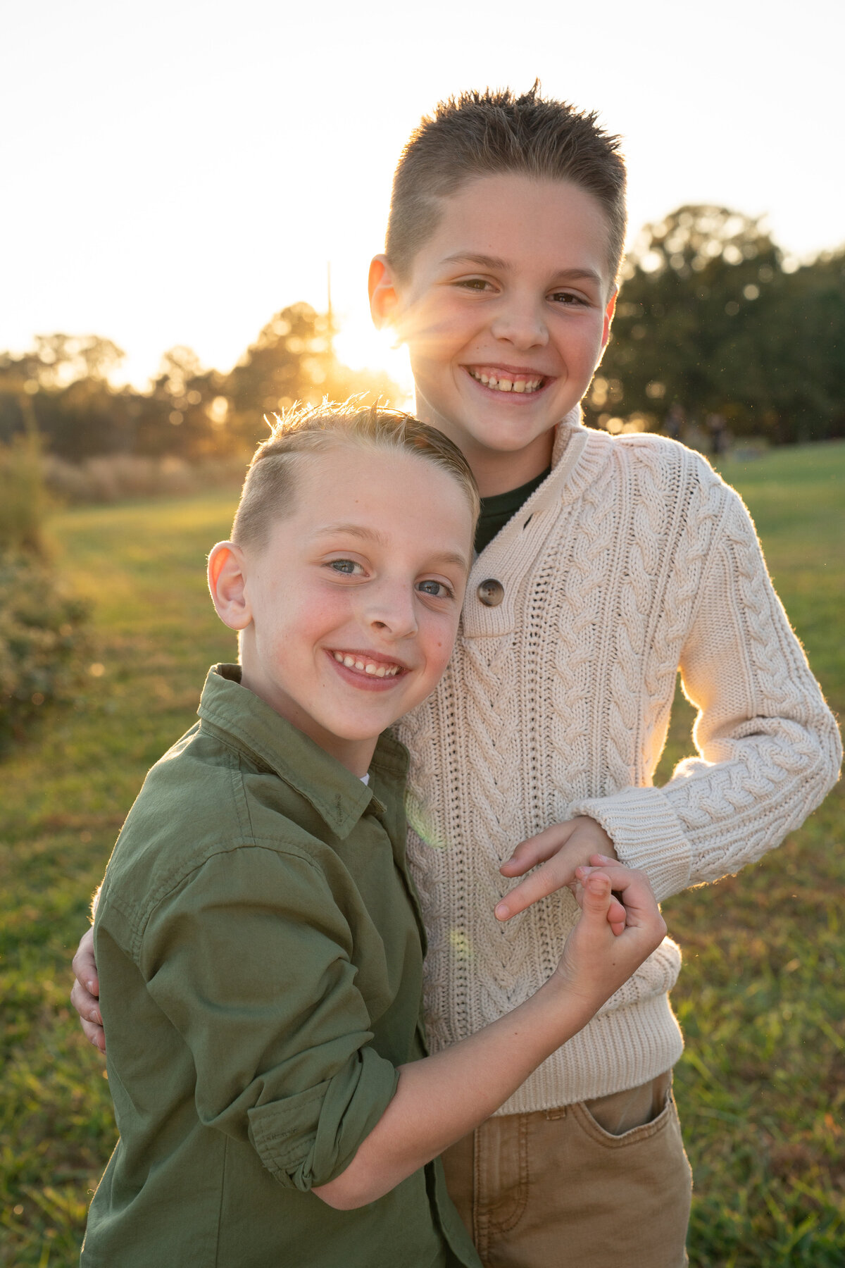 Brothers hugging with sun setting behind them during fall. 