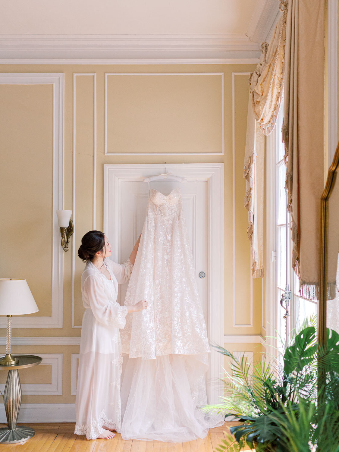Bride looks at her wedding dress hanging on a door