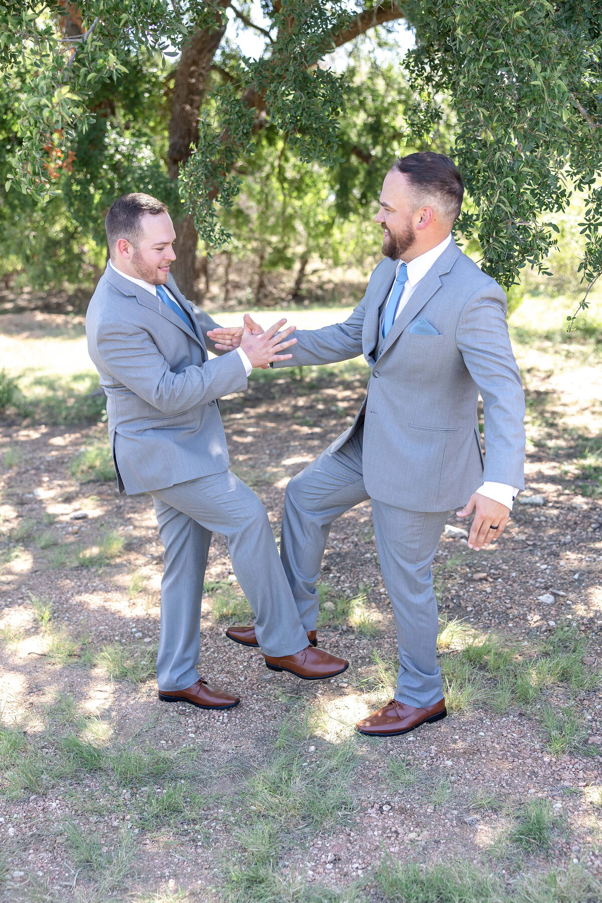 groom and groomsman in playful pose tapping shoes at Dripping Springs wedding Morgan Creek Barn