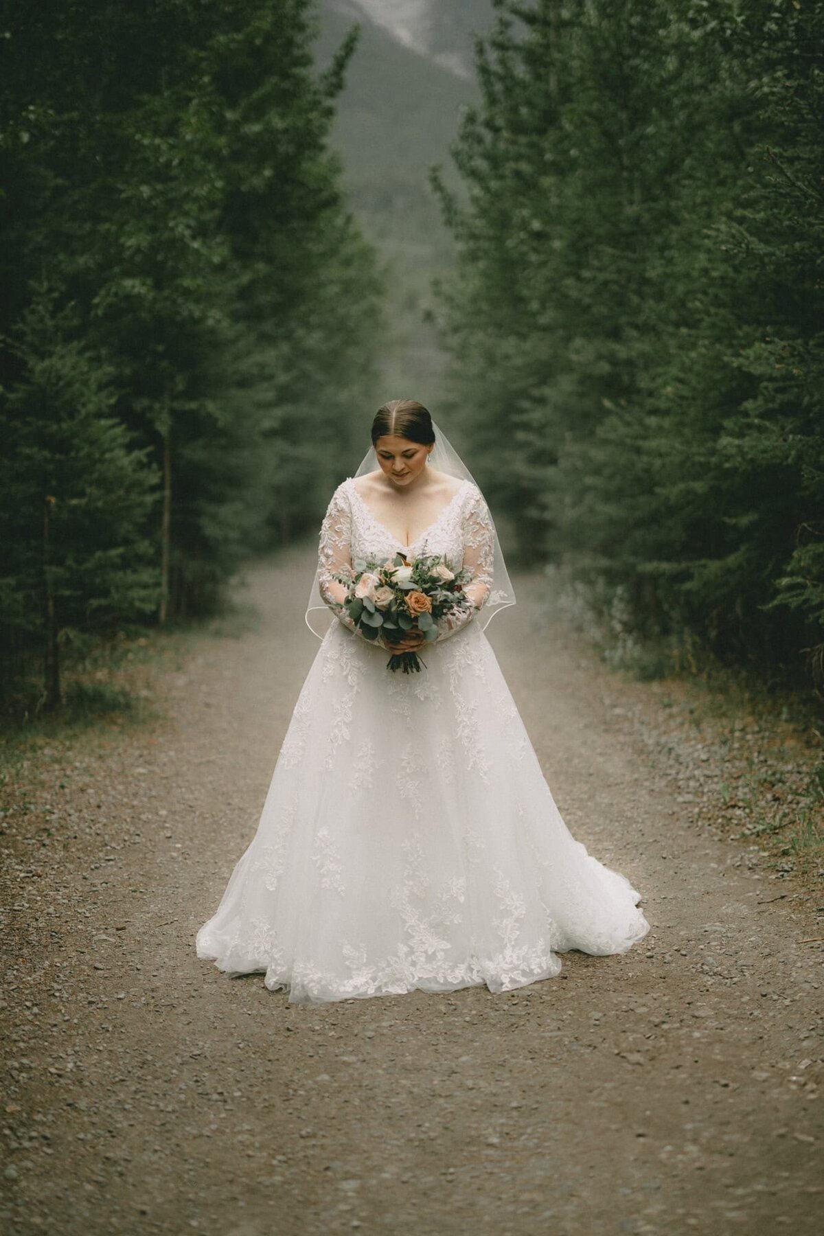 Bride standing in woods holding flowers