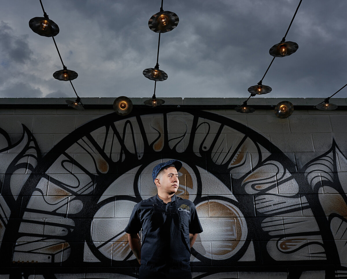 A man looking off while standing in front of a mural