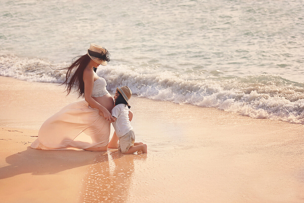Pregnant mama by the beach with her son kissing her stomach by Yuliia Terziian Photography.