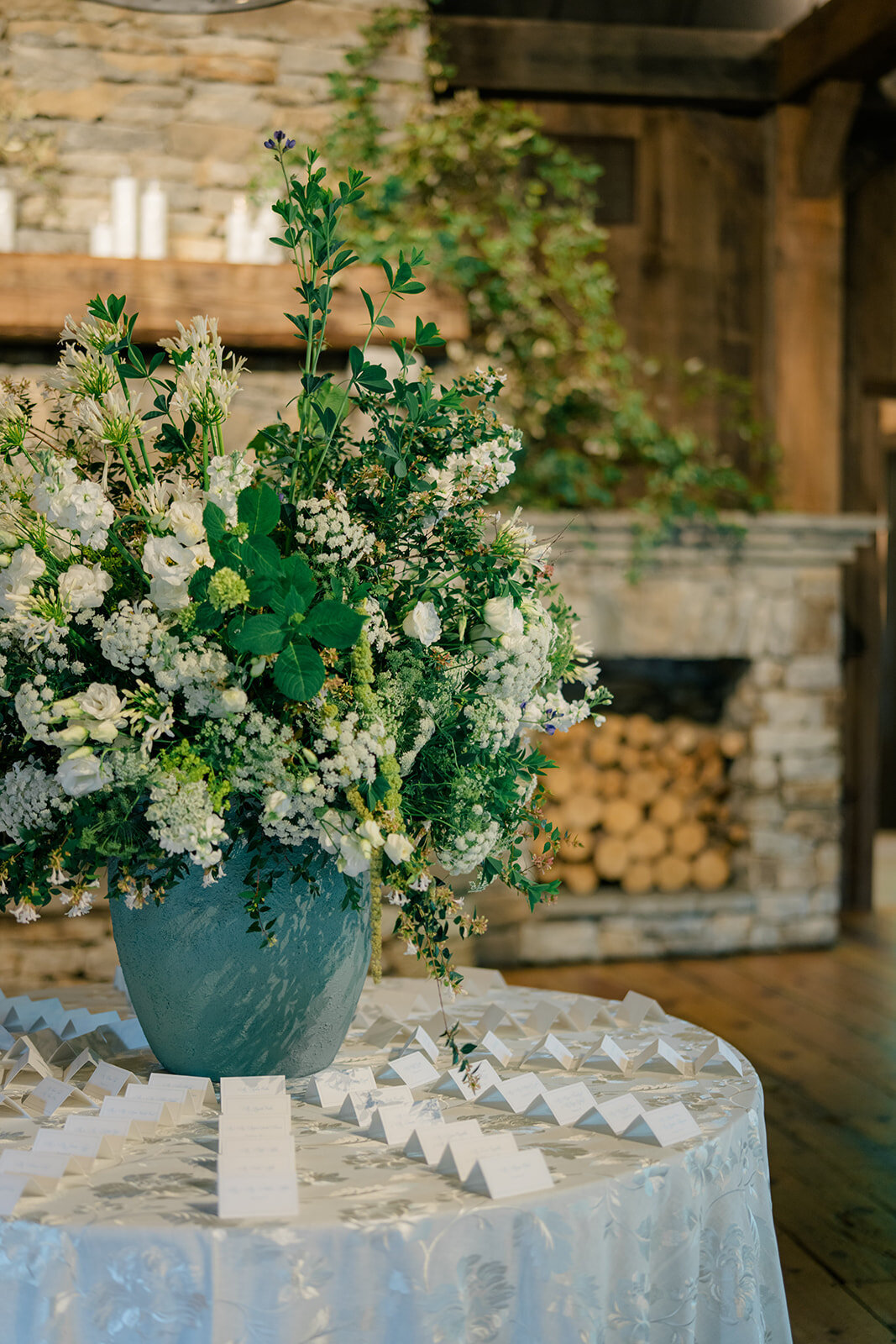 Escort card table with overflowing floral arrangement at reception entrance.