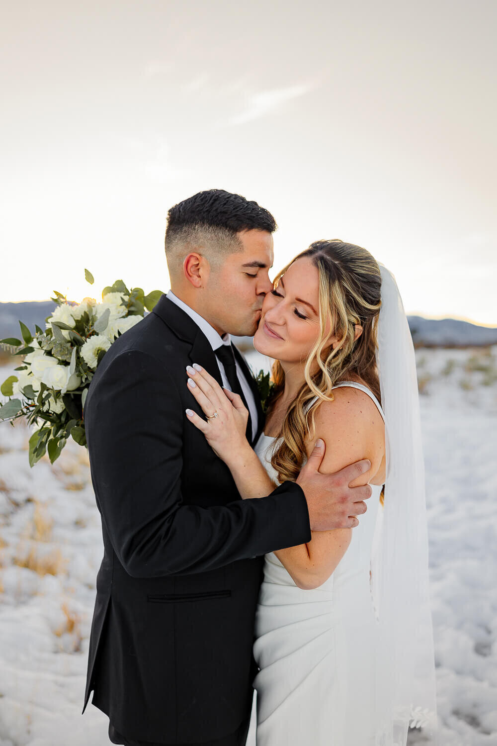 Bride and groom embracing each other in the beautiful snow and mountains. Captured by Colorado Springs wedding photographer, Michelle Betz Photography