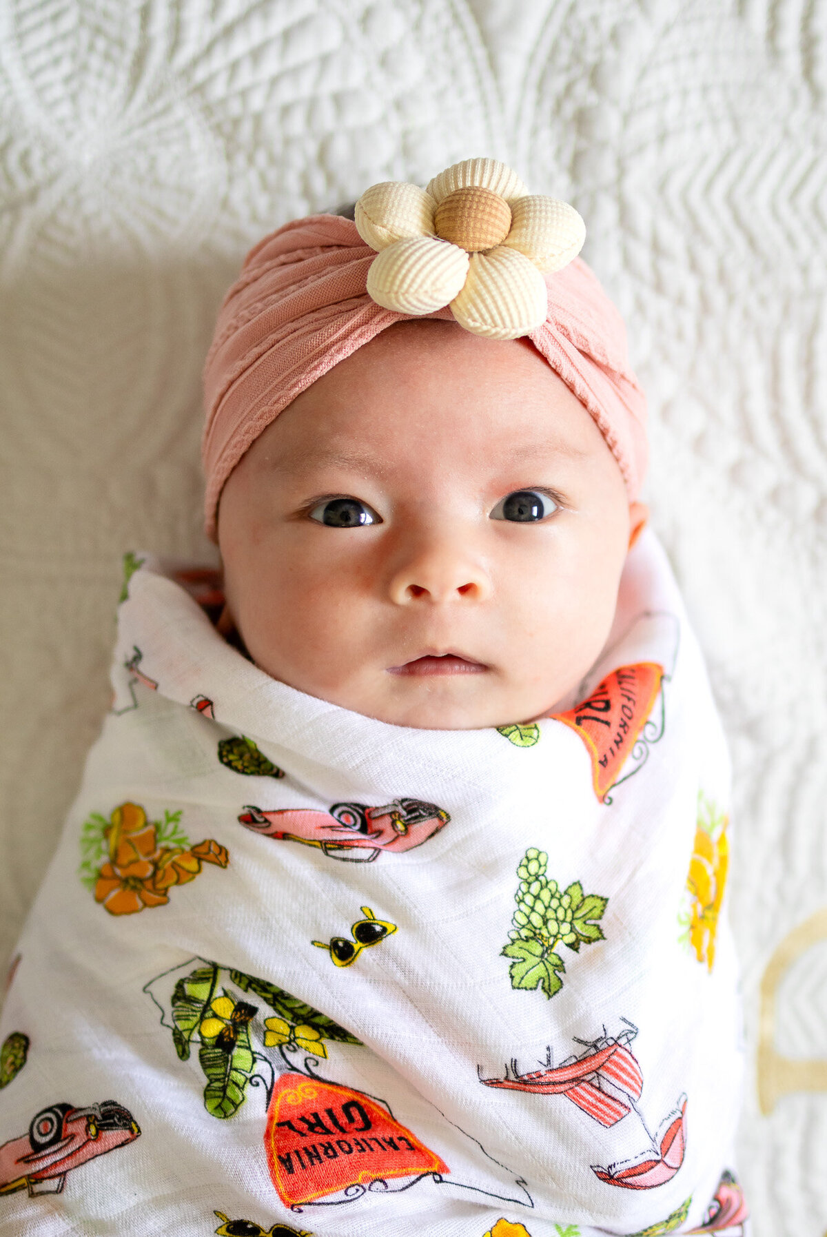 newborn headshot swaddled in muslin blanket with flower headband captured by San Francisco newborn photographer.