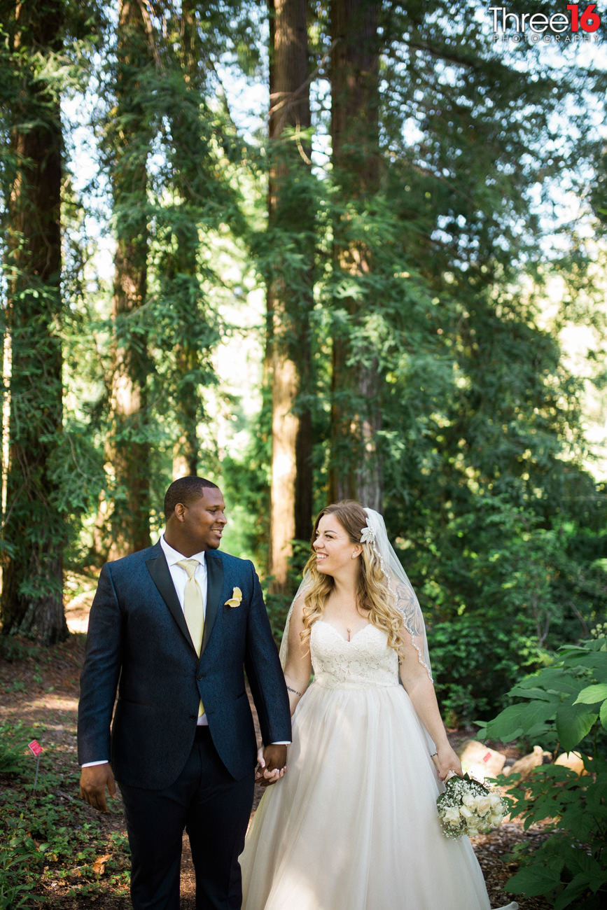Bride and Groom go for a walk in the woods holding hands and smiling at each other