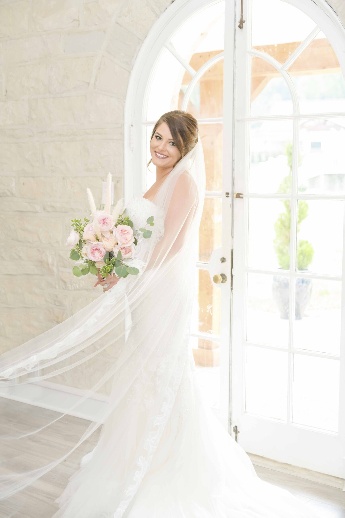Bride standing in front of a backlit window in the bridal suite of Knotting Hills Wedding Venue