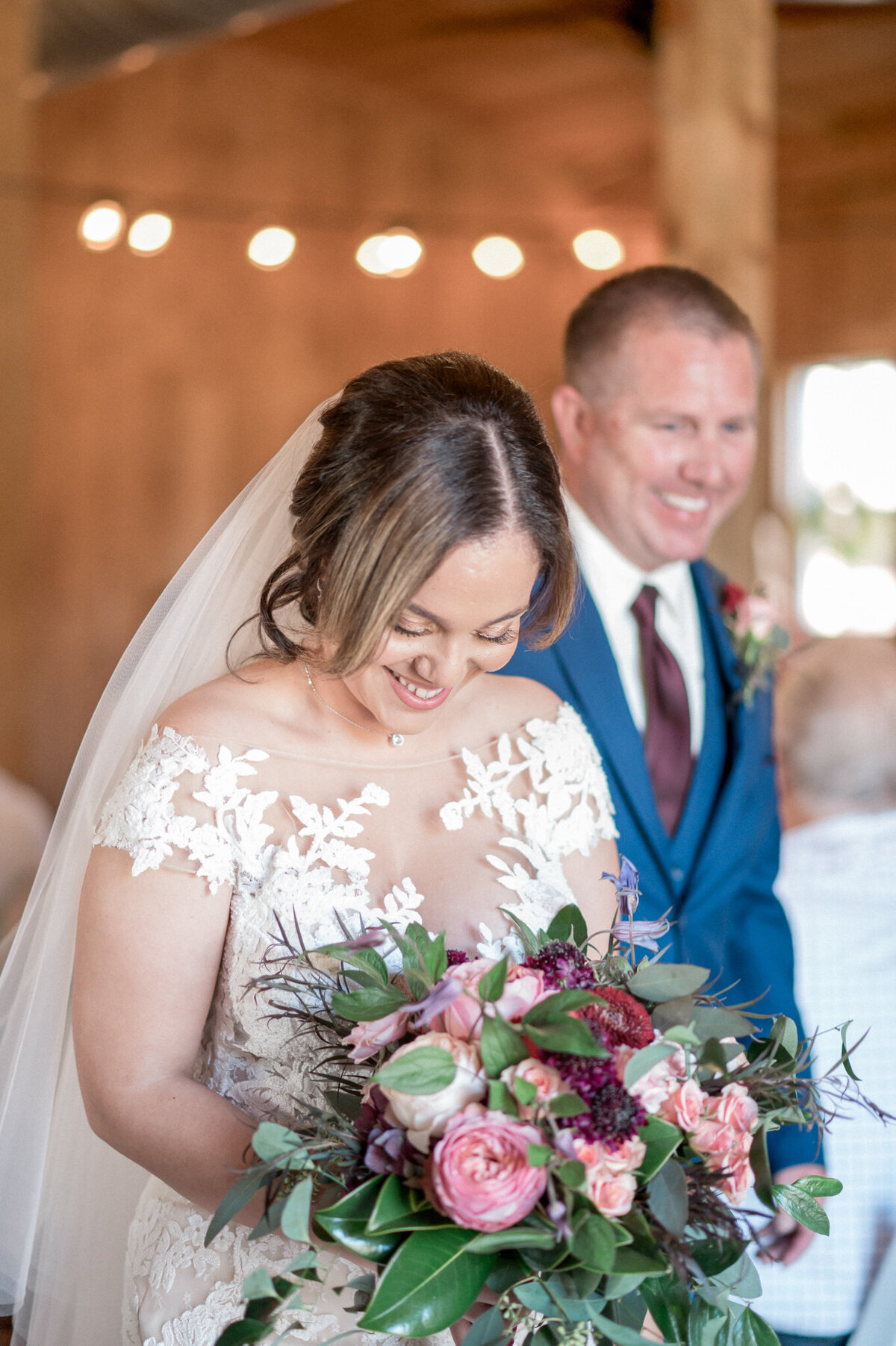 The bride, with a huge smile on her face, looks down at her bouquet as she exits the wedding ceremony with her new husband
