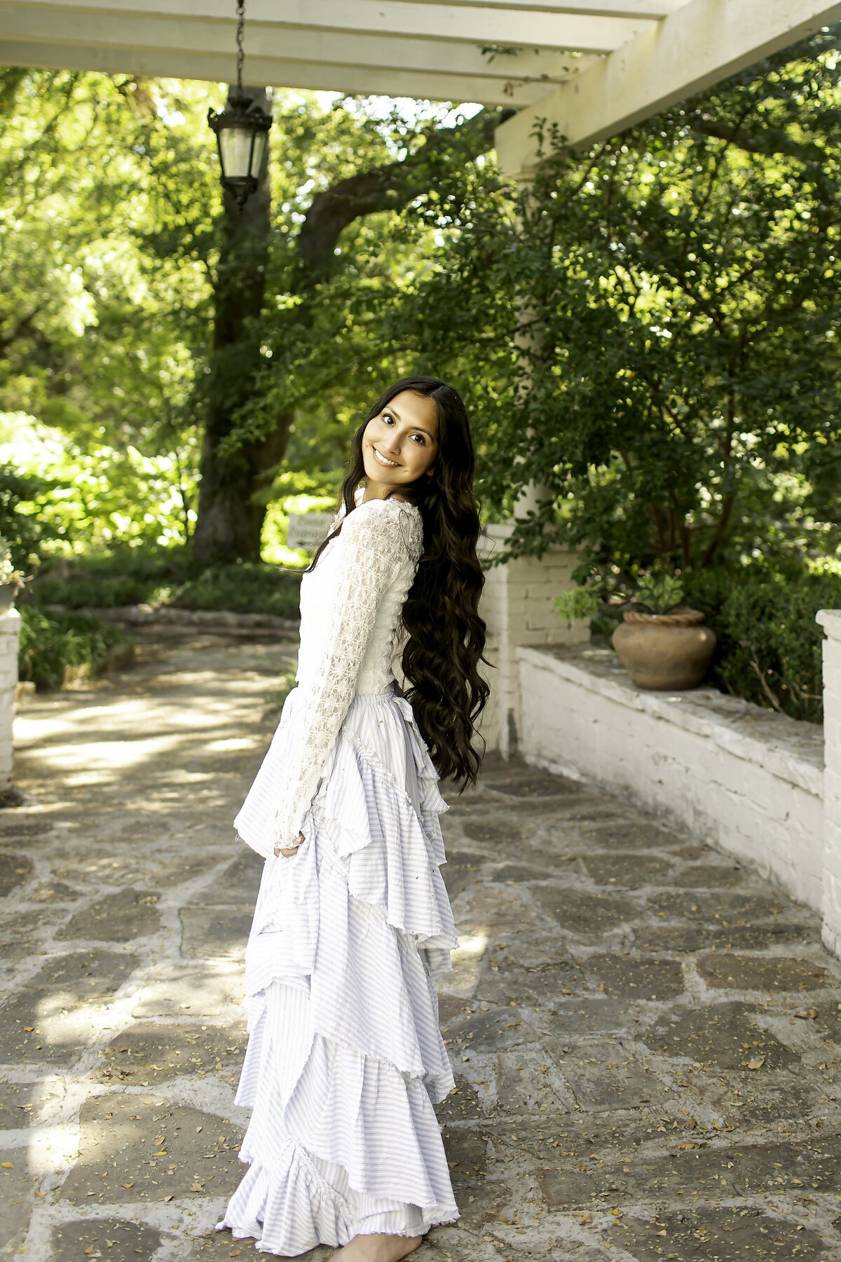 Captured in a dreamlike moment, a high school senior poses in a soft dress surrounded by the vibrant, blooming flowers of Chandor Gardens, creating a timeless photo