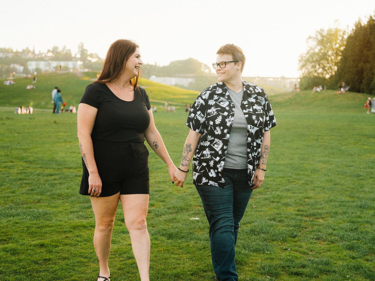 LGBTQ couple holds hands and walks towards the camera in sunset light