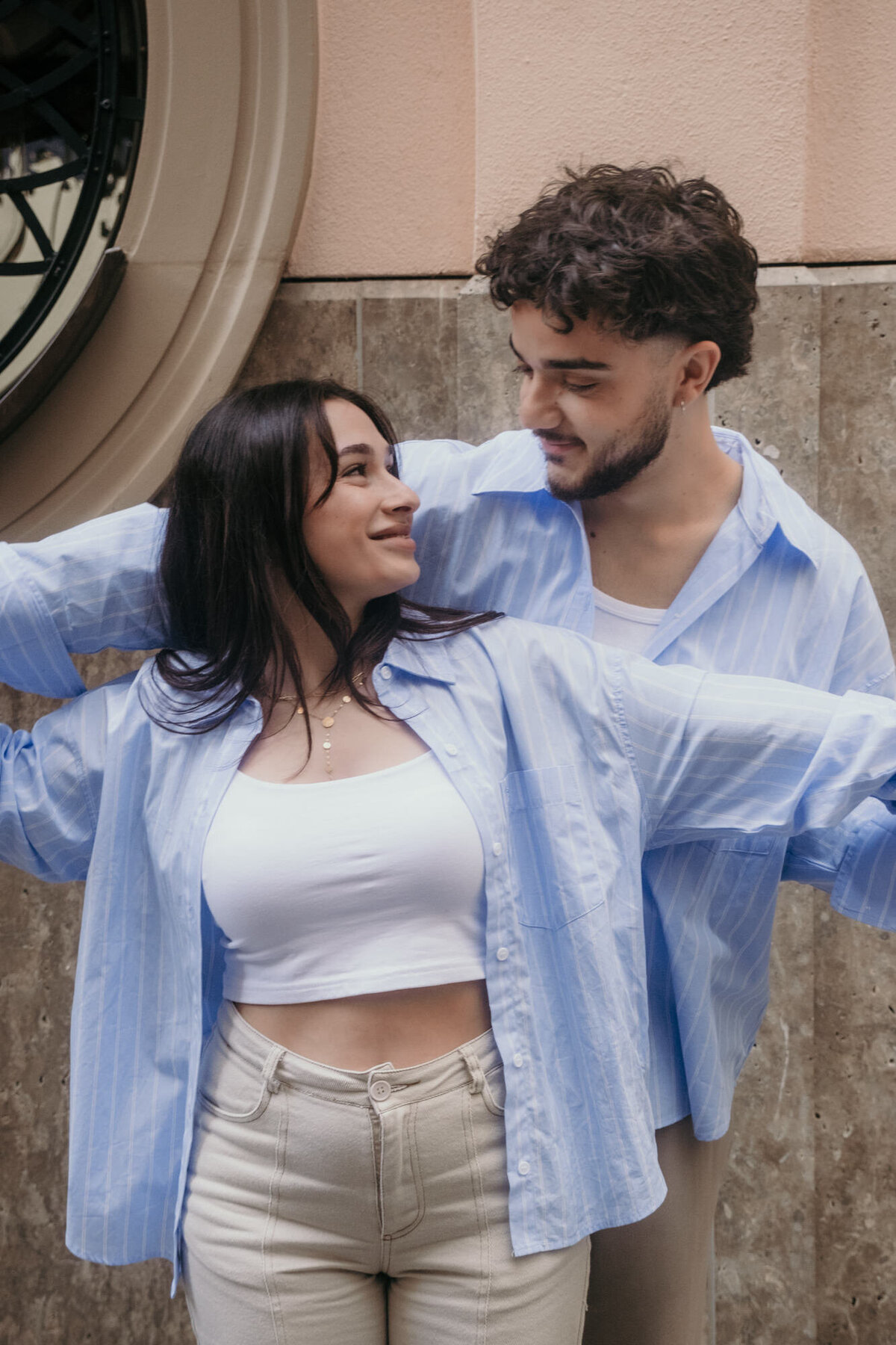 The woman turns back at her partner as she smiles at him, while holding his hands.