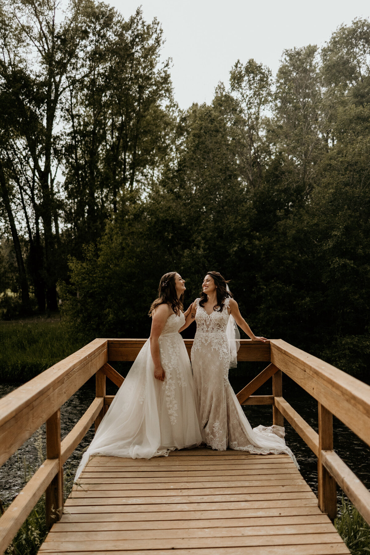 two brides standing on a dock together over a river