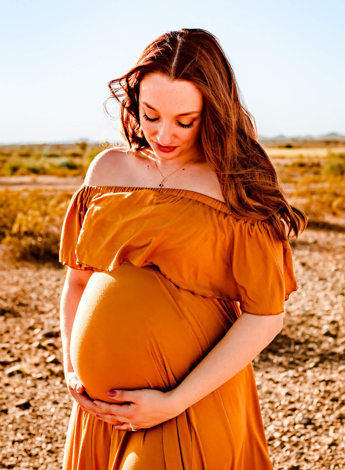 first time mom holding her maternity belly for her photography session in Arizona