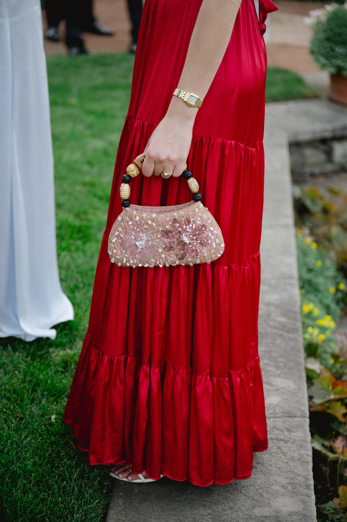 Detail of a bridesmaid's red pleated dress with decorative shoulder clasps at the Chicago Botanic Gardens