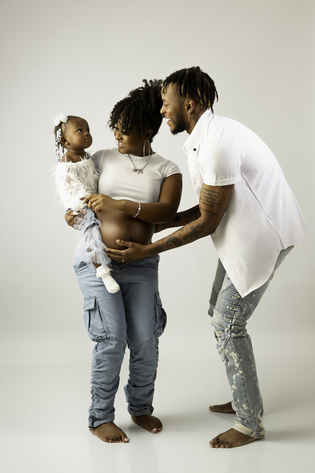 Family of three smiling at toddler daughter in Chattanooga Studio during photoshoot.