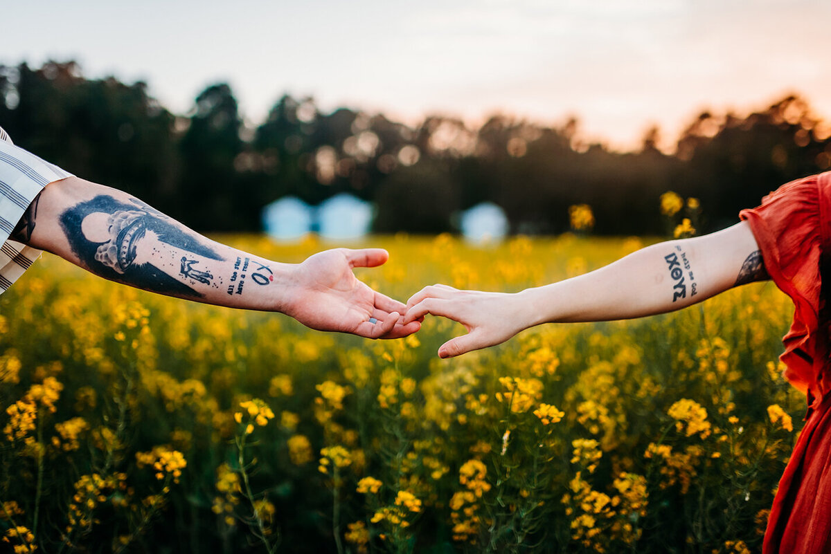 an artsy picture of a couples hands interlocking in a field of wildflowers