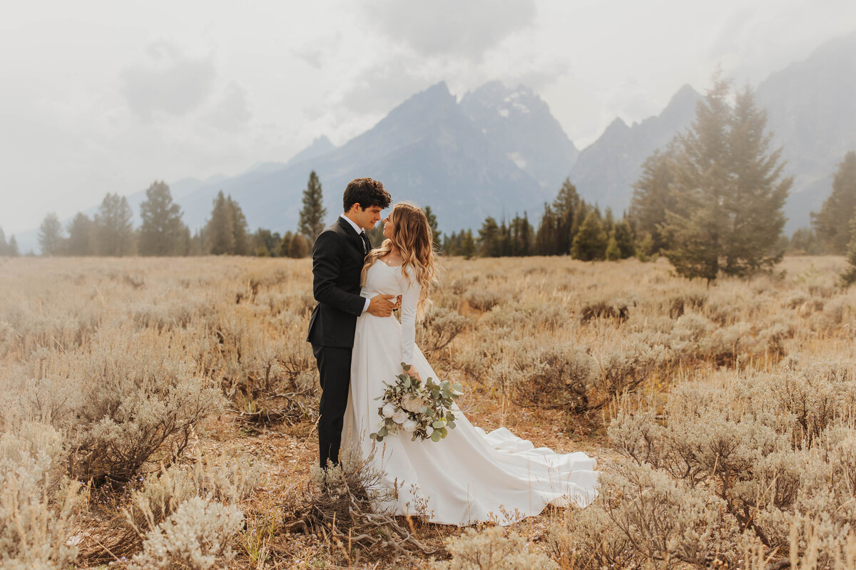 bride and groom embracing by mountain