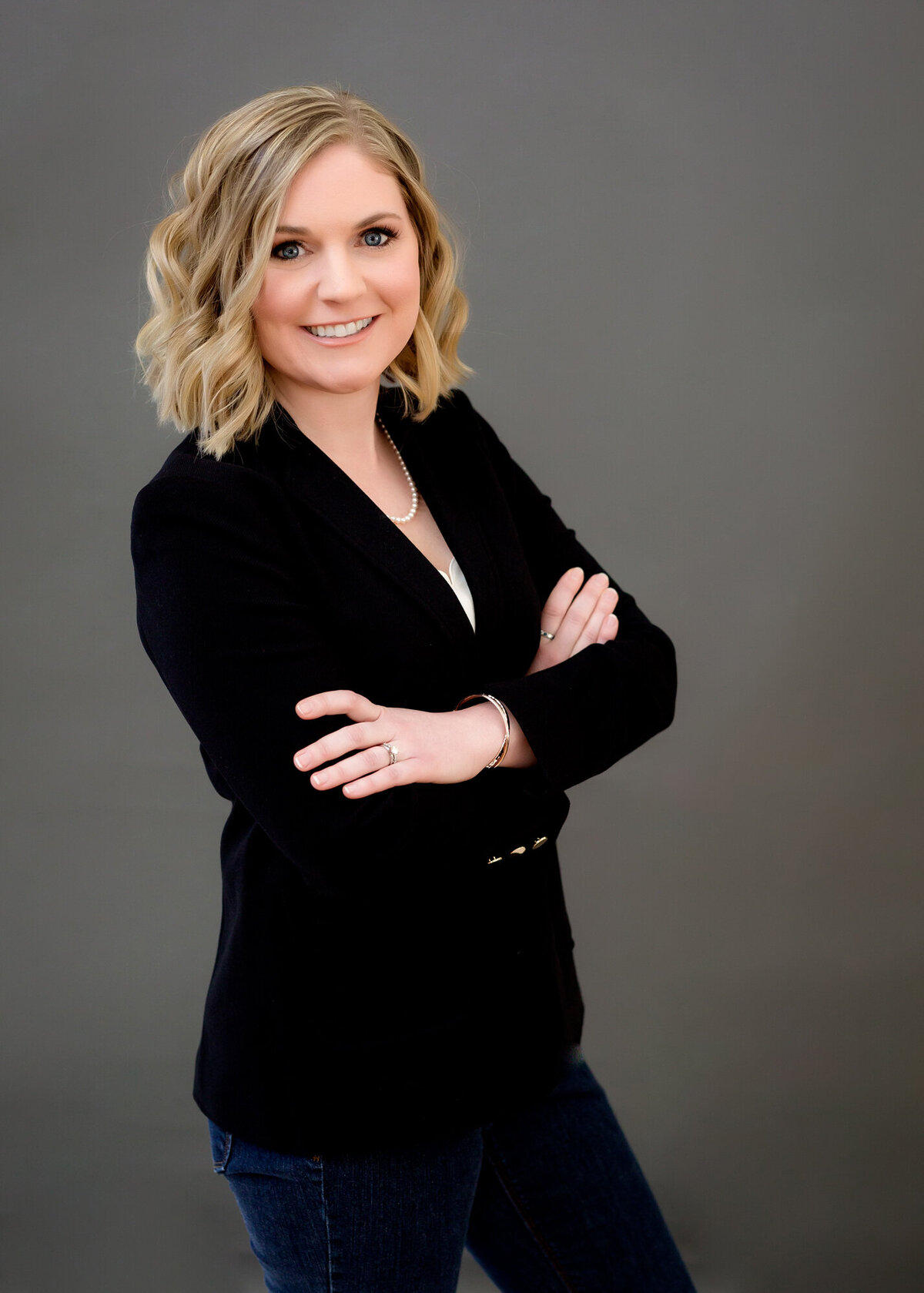 Female headshot client wearing a black suit in a power pose of arms crossed