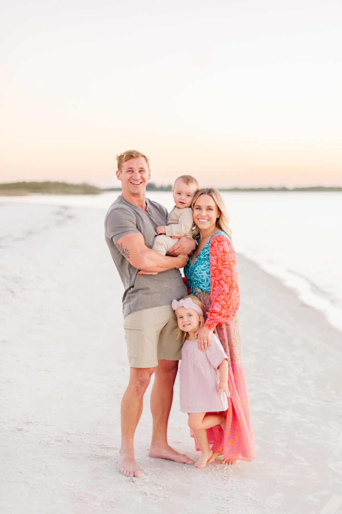 Family of four smile for a portrait near the water at a beach east of Orlando