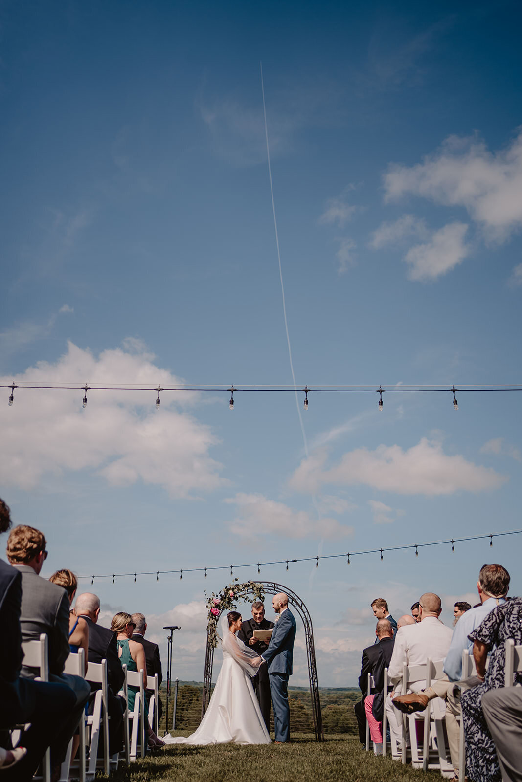 String lights hanging over an outdoor wedding ceremony 