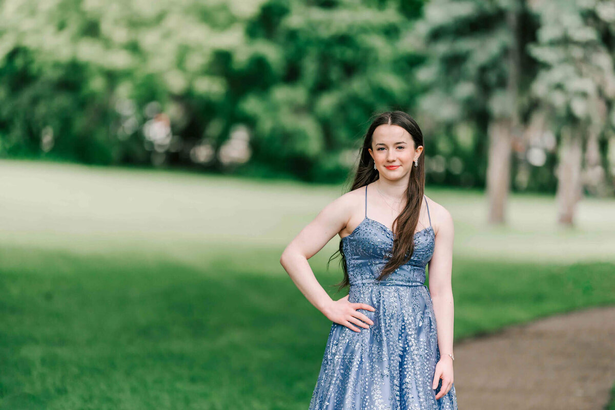 Brunette girl standing with hand on hip in a purple dress.