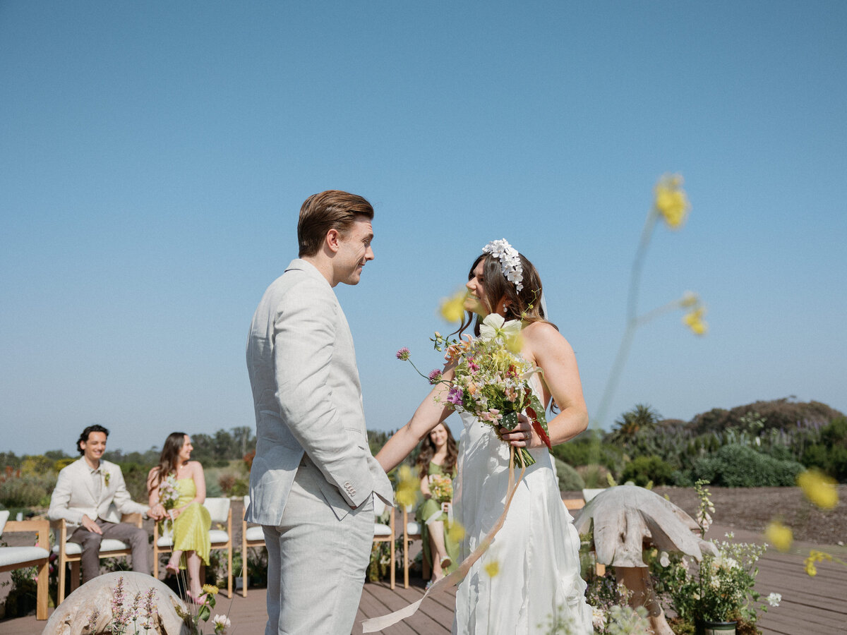 Couple exchanging vows under clear blue skies at their La Jolla wedding in San Diego, California.
