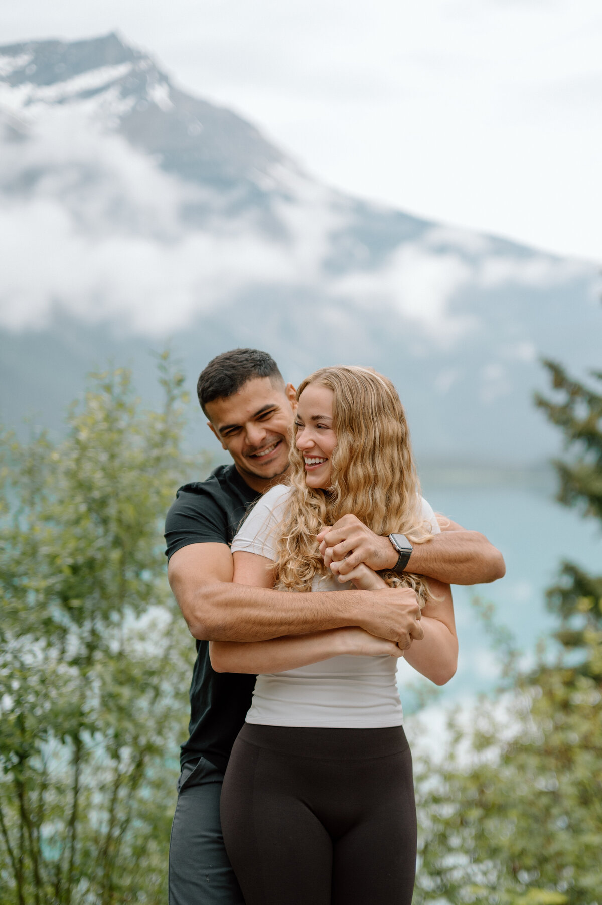 Candid laughing moment between couple after rainy Emerald Lake proposal.