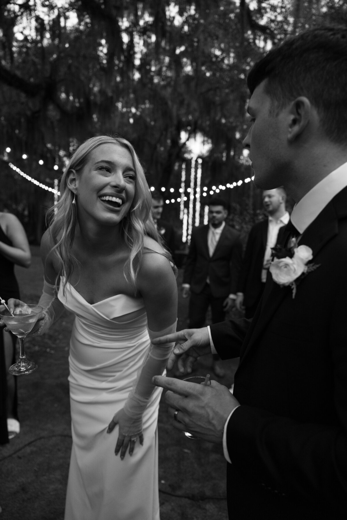 Candid moment of the couple laughing together under a canopy of trees