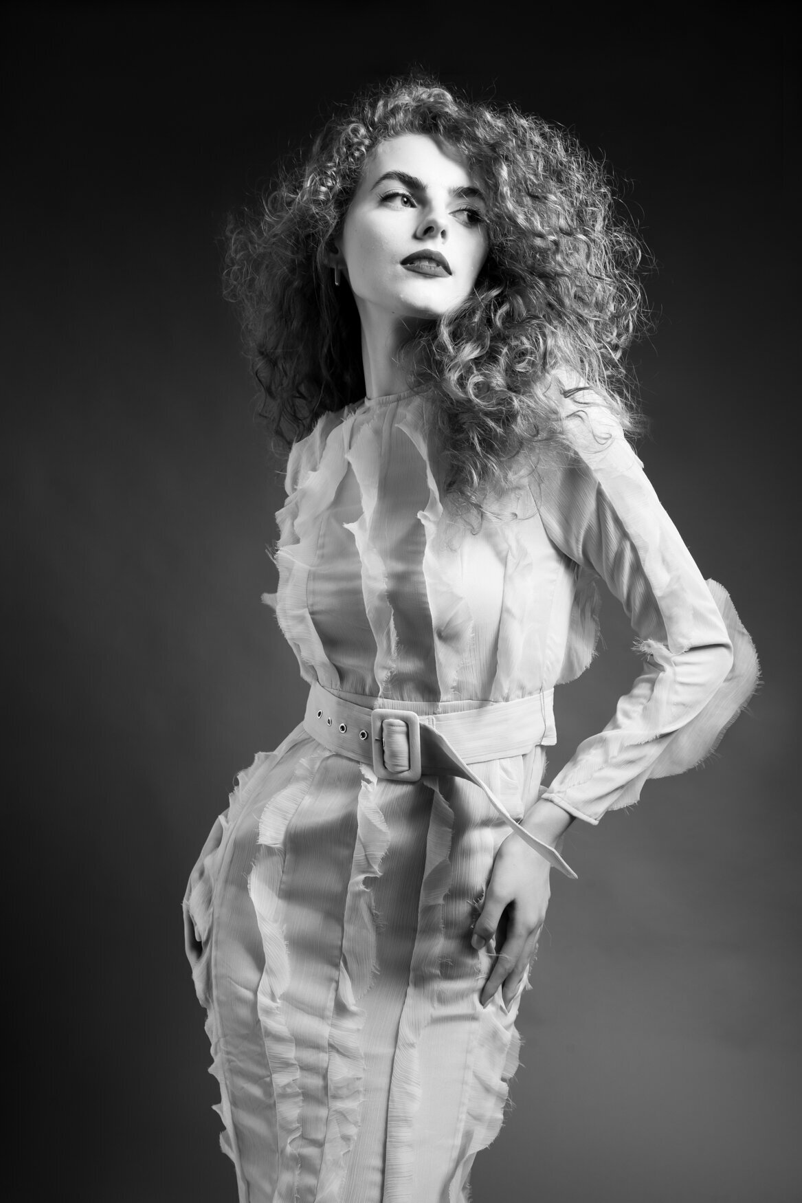 Portrait of a woman standing with her head tilted looking to the side and her hands on her hips