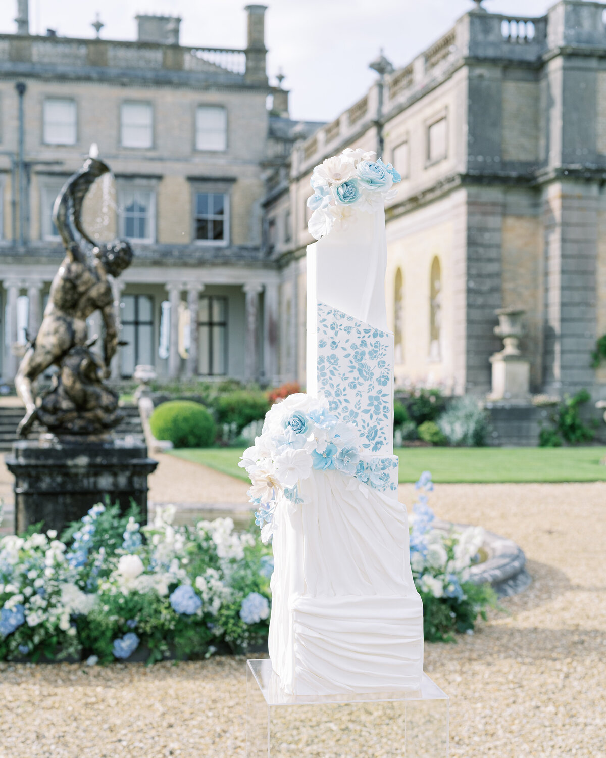 White and blue wedding cake and flowers at Somerley House wedding venue