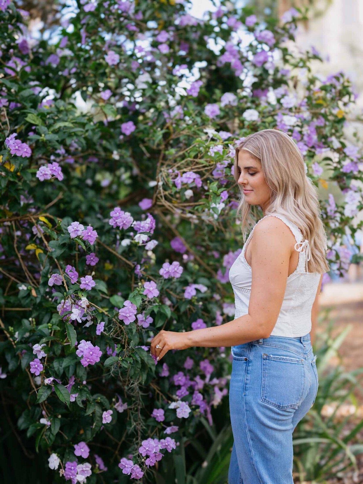 Florida bride touching purple blooms while admiring her engagement ring in Charleston, SC.