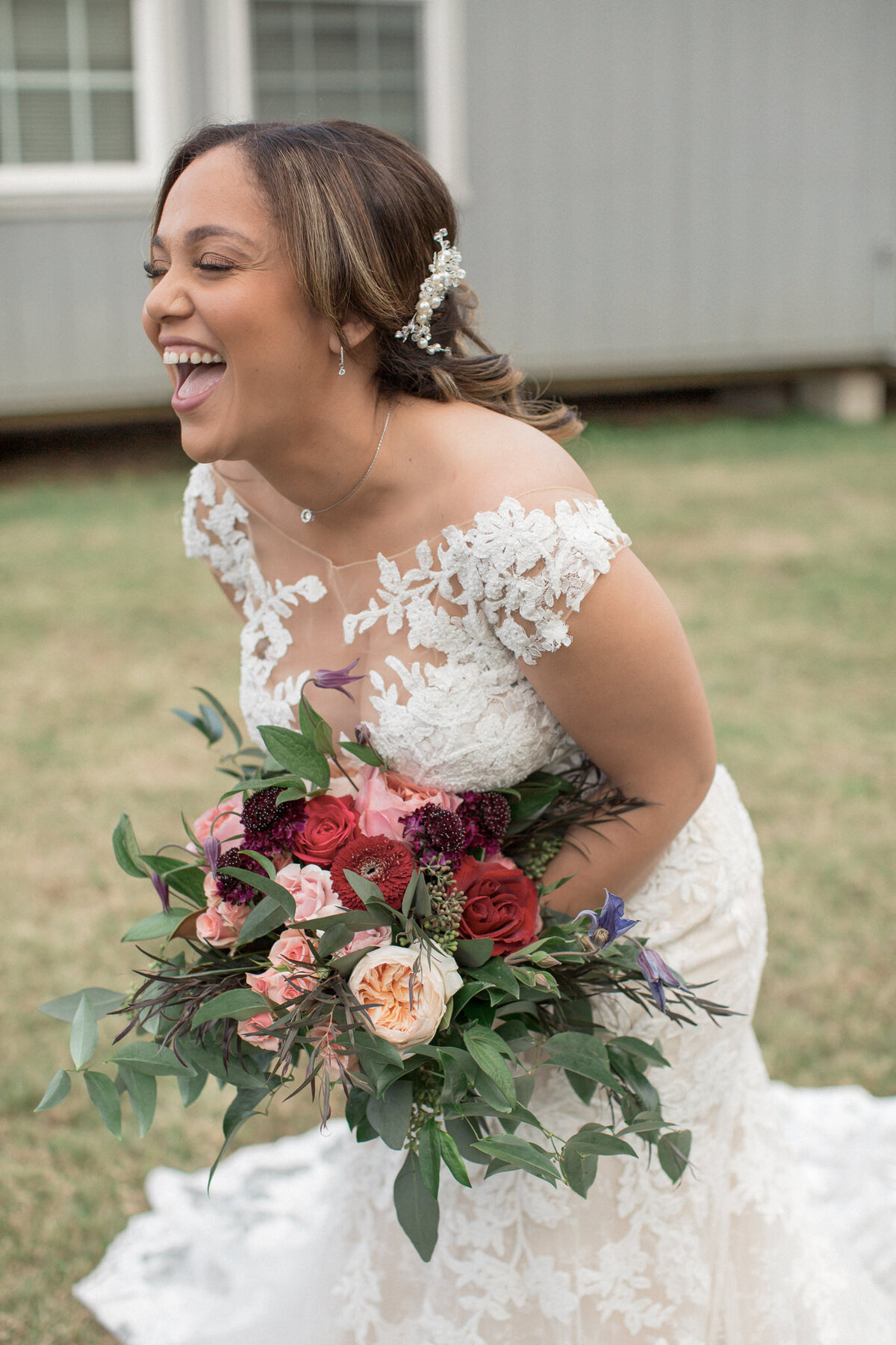 A bride laughing joyfully as she carries a stunning bouquet full of roses and eucalyptus