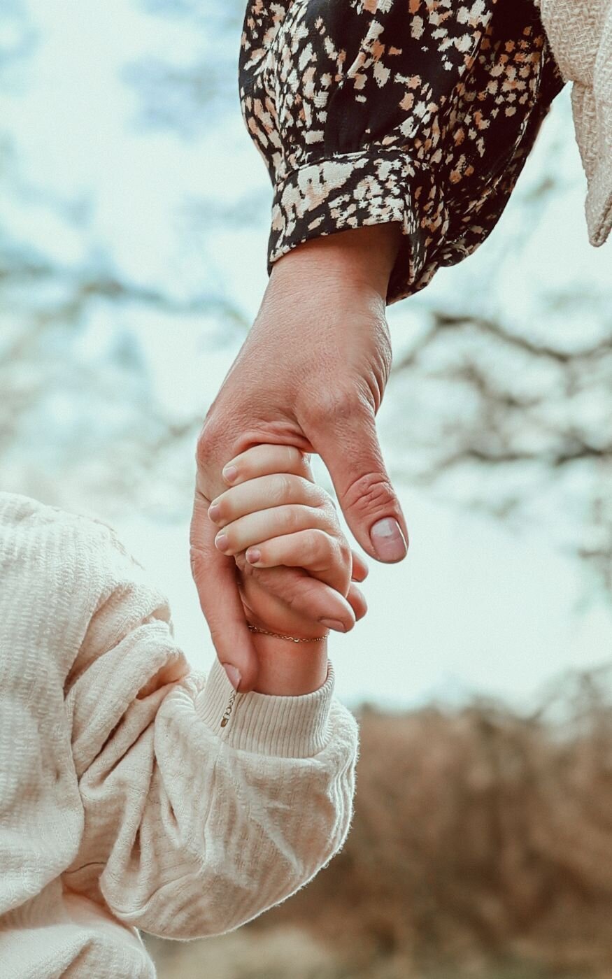 De hand van een volwassene omvat zachtjes de hand van een pasgeboren baby