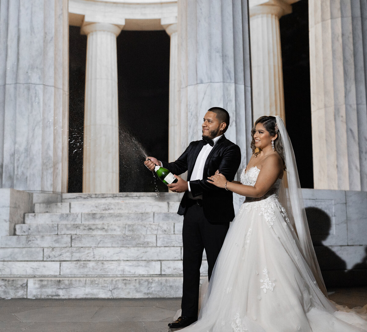 bride and groom spraying champagne wearing black suit and white dress in washington dc
